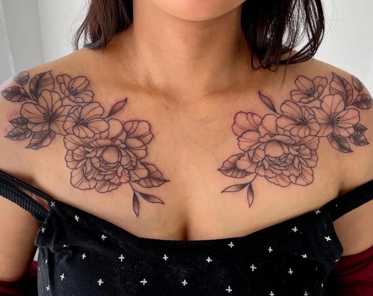 Fine line floral tattoo across the chest and shoulder