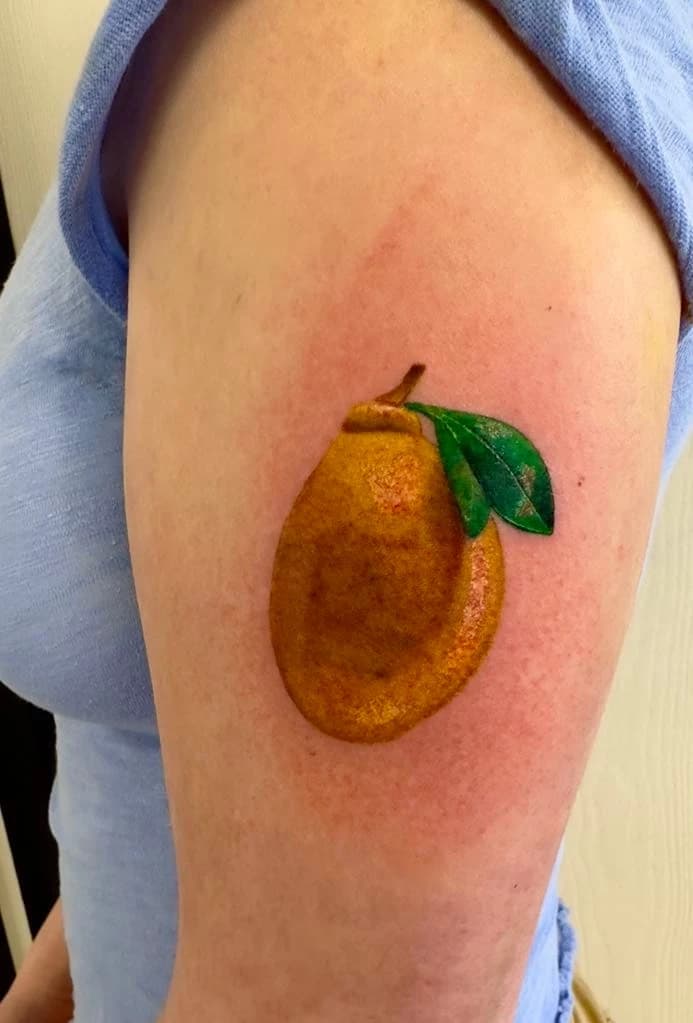 Small color realism lemon tattoo on the upper arm by Carlos Barrera