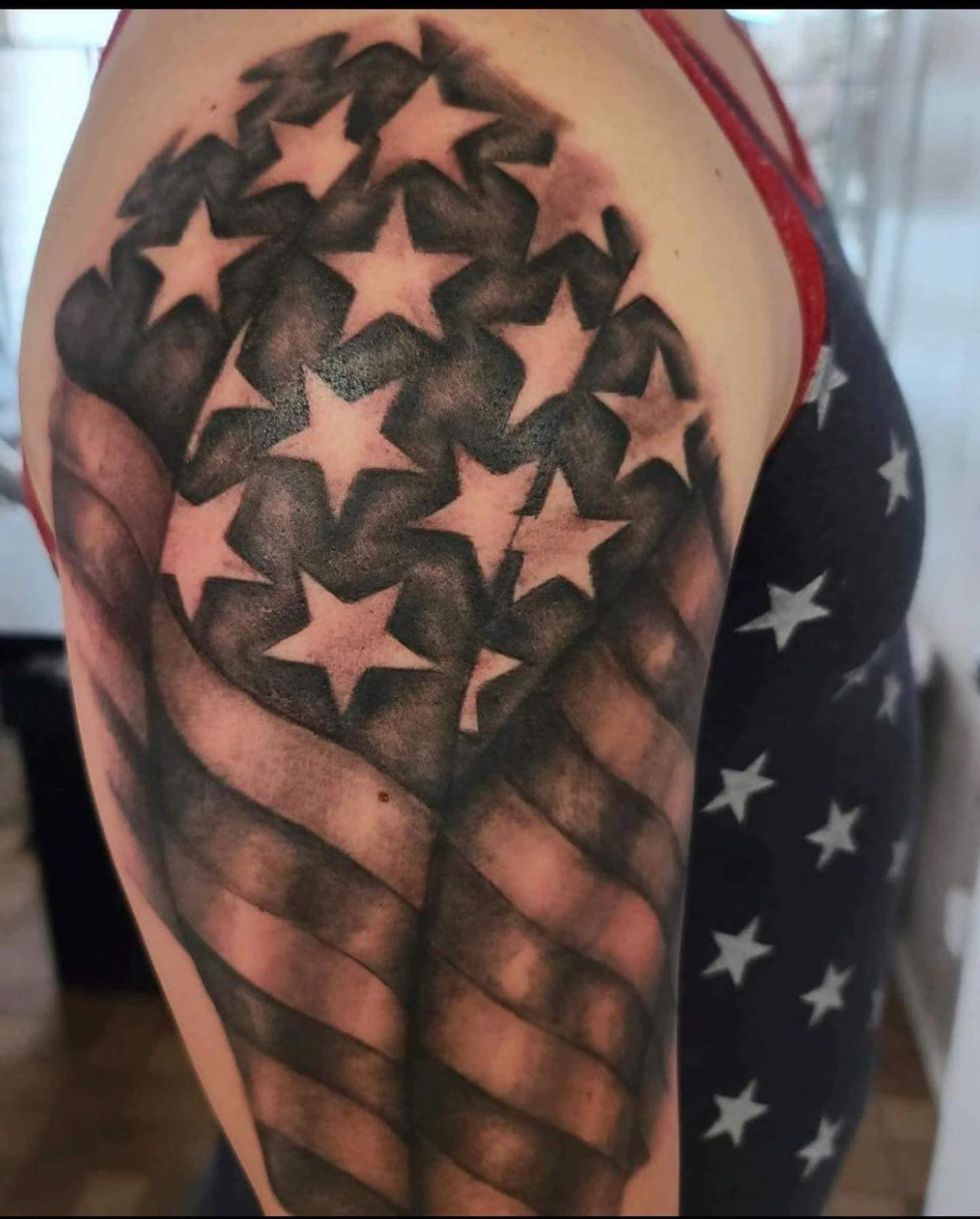 Black and grey realism American flag tattoo on the upper arm