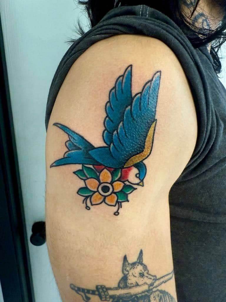 Traditional swallow and flower tattoo on the upper arm