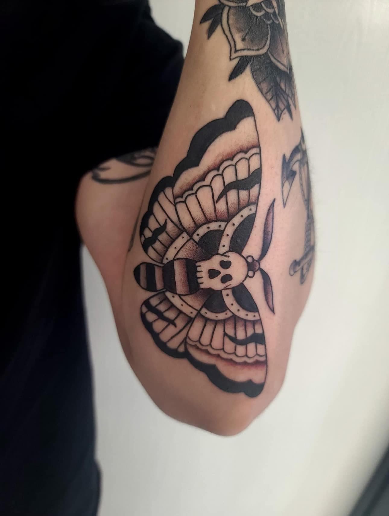 Traditional death moth tattoo on the elbow